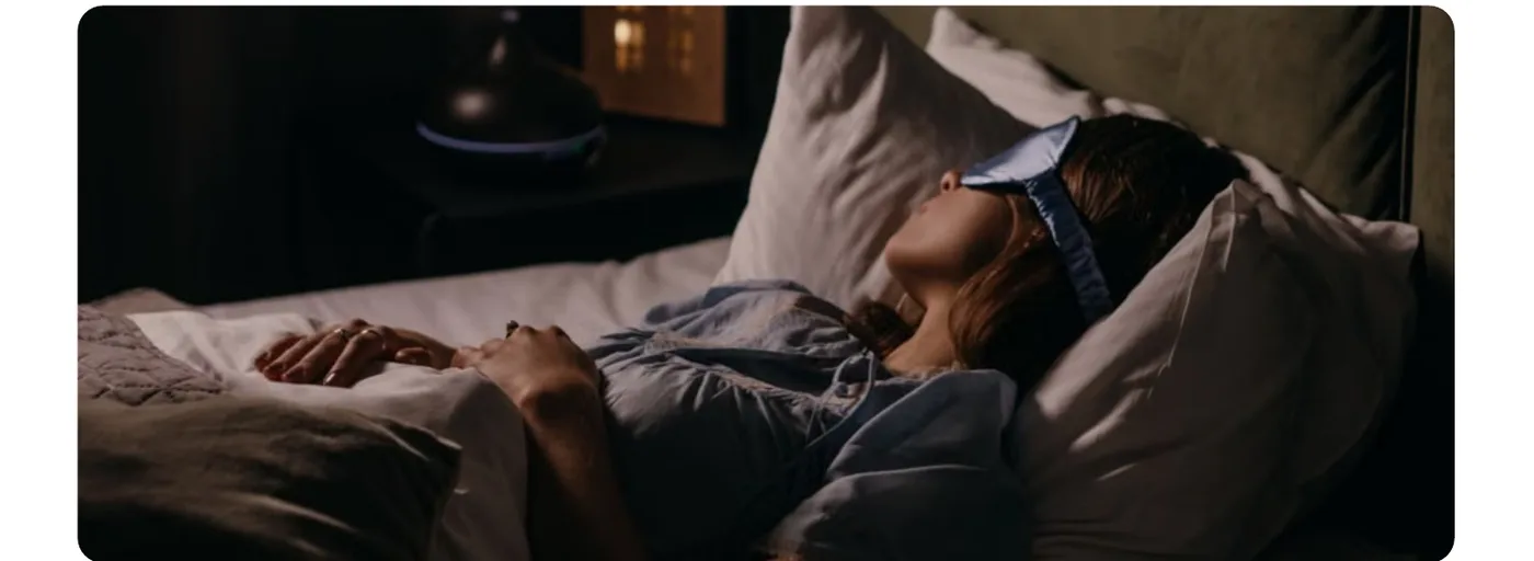 Pessoa deitada na cama à noite, com luz de cabeceira acesa