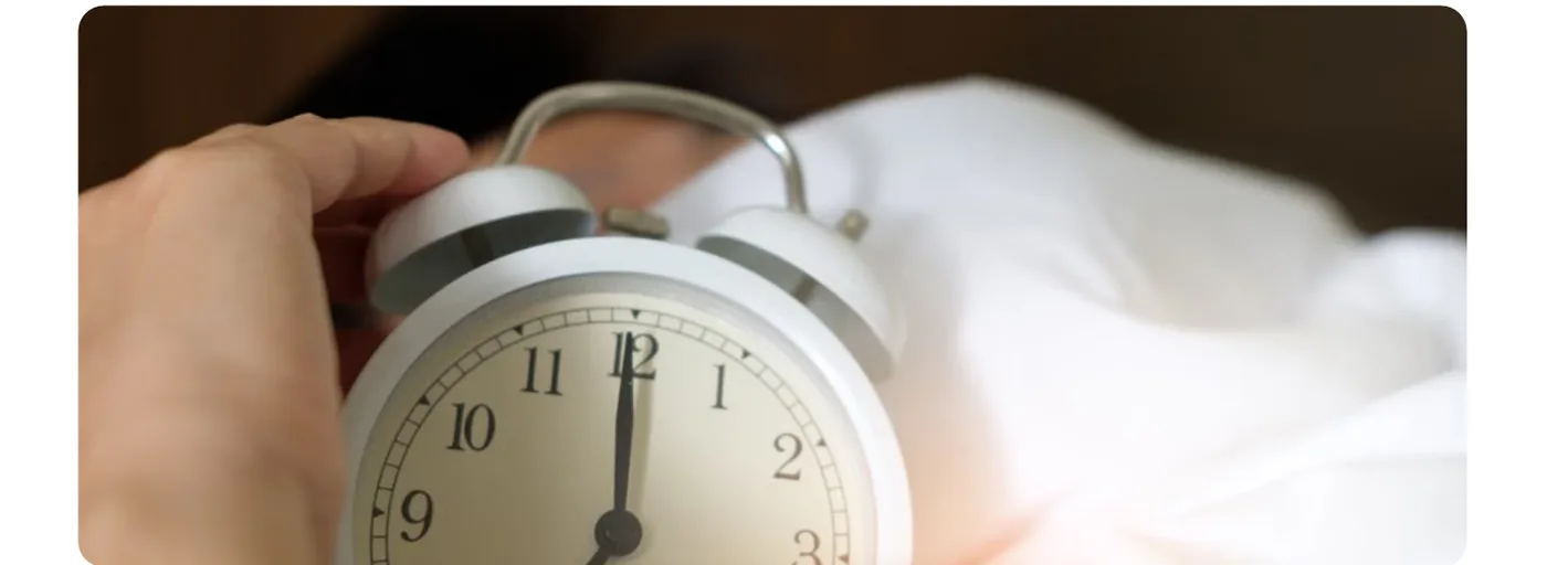 Mão desligando um despertador na cama, de madrugada